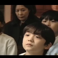 Di akhir video, aktris Moon So Ri muncul sebagai wanita misterius, mengawasi bocah yang menahan jari Byeon Woo Seok. Lewat project The Christmas Song, sutradara Shin Woo Seok kembali menuai pujian dengan visual dan narasinya. Ialah yang menggarap video klip Ditto, OMG, dan Cool With You dari NewJeans. Foto: dok. YouTube @DolphinersOfficial