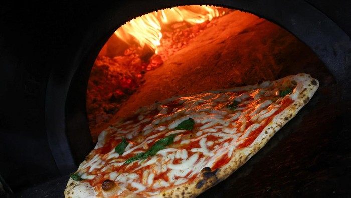 A pizza is taken out from a wood-fired oven at Lantica Pizzeria da Michele as Italian cuisine awaits a crucial UNESCO decision that could recognise it as an Intangible Cultural Heritage of Humanity in Naples, Italy, December 5, 2025. REUTERS/Ciro De Luca