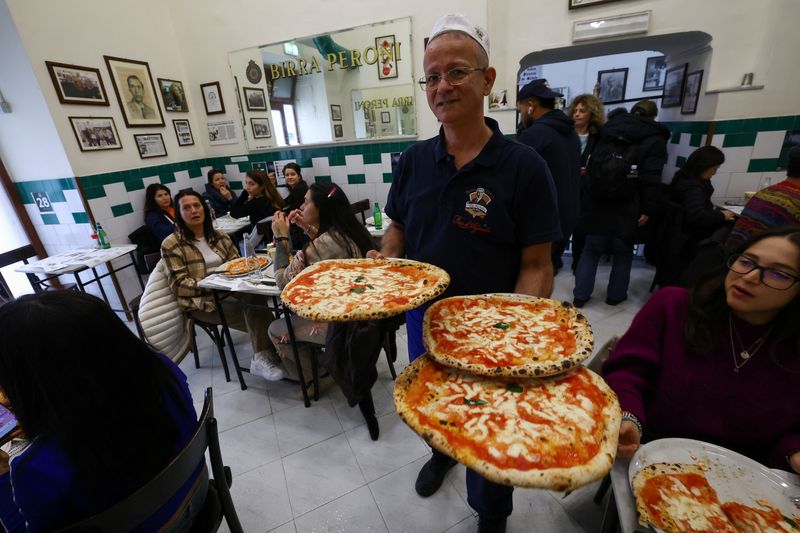 Pasta hingga Pizza, Italia Bidik Status Warisan Dunia dari UNESCO A waiter carries pizzas at L'antica Pizzeria da Michele as Italian cuisine awaits a crucial UNESCO decision that could recognise it as an Intangible Cultural Heritage of Humanity in Naples, Italy, December 5, 2025. REUTERS/Ciro De Luca