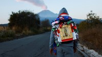 Seorang peziarah yang membawa patung Bunda Maria Guadalupe berjalan menuju Basilika Guadalupe di Kota Meksiko melalui celah gunung antara gunung berapi Popocatepetl dan Iztaccihuatl, yang dikenal sebagai Paso de Cortes, menjelang hari raya tahunan Bunda Maria Guadalupe, di Santiago Xalitzintla di negara bagian Puebla, Meksiko, Selasa (9/12/2025). REUTERS/Raquel Cunha