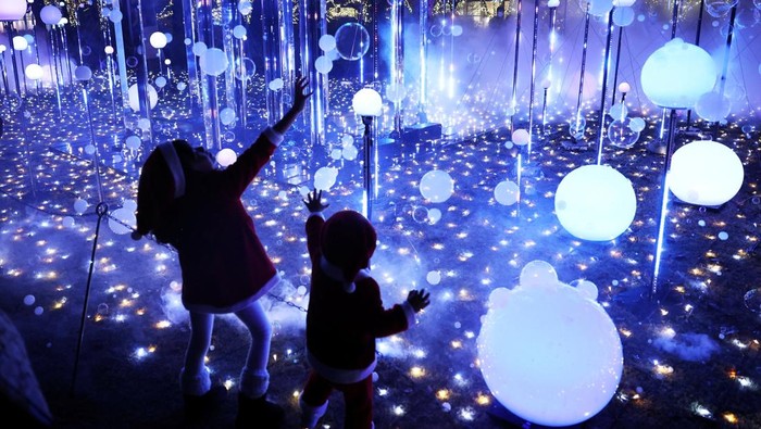 A 6-year-old girl wearing a Santa Claus costume tries to catch soap bubbles in the air at an illumination event celebrating the upcoming the Christmas season at a park in Tokyo, Japan December 3, 2025. REUTERS/Issei Kato TPX IMAGES OF THE DAY