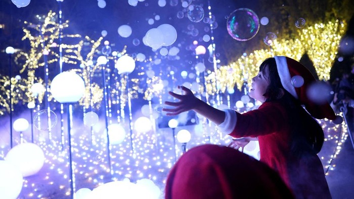 A 6-year-old girl wearing a Santa Claus costume tries to catch soap bubbles in the air at an illumination event celebrating the upcoming the Christmas season at a park in Tokyo, Japan December 3, 2025.  REUTERS/Issei Kato     TPX IMAGES OF THE DAY