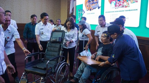 upati Badung, I Wayan Adi Arnawa, menyerahkan bantuan kursi roda kepada Agus Mertayasa, pelukis disabilitas asal Desa Buduk, Kecamatan Mengwi, yang hadir saat penyerahan bantuan di Puspem Badung, Rabu (10/12/2025). (Agus Eka/detikBali)