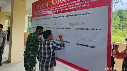 Perwakilan Forum Kepala Desa Kecamatan Pujut, Lombok Tengah, Lalu Minaksa saat menandatangani petisi penolakan tambang yang ada di Dusun Kuta Dua, Kamis (11/12/2025).