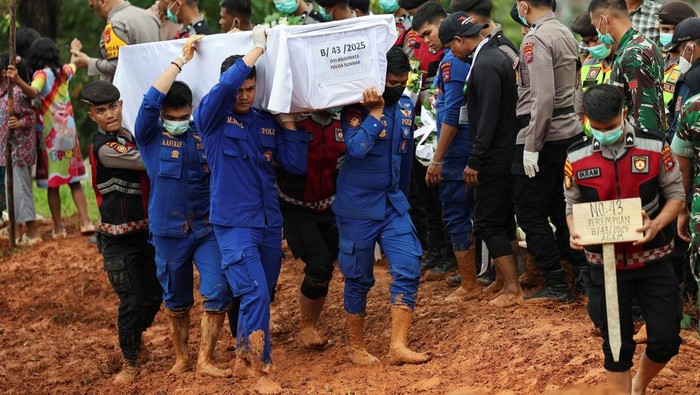 Police officers carry a coffin of an unidentified victim of the recent flash floods and landslides, during a mass funeral in Padang, West Sumatra province, Indonesia, December 10, 2025. REUTERS/Willy Kurniawan