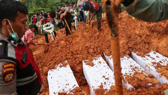 Police officers burry coffins of unidentified victims of the recent flash floods and landslides, during a mass funeral in Padang, West Sumatra province, Indonesia, December 10, 2025. REUTERS/Willy Kurniawan