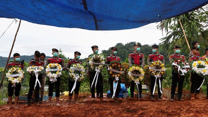 Police officers carry wreaths to be placed on the graves of unidentified victims of the recent flash floods and landslides, during a mass funeral in Padang, West Sumatra province, Indonesia, December 10, 2025. REUTERS/Willy Kurniawan