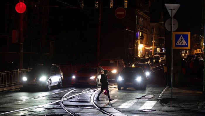 A woman crosses an unlit street during a power blackout after critical civil infrastructure was hit by recent Russian missile and drone attacks, amid Russia's attack on Ukraine, in Kyiv, Ukraine December 10, 2025. REUTERS/Thomas Peter