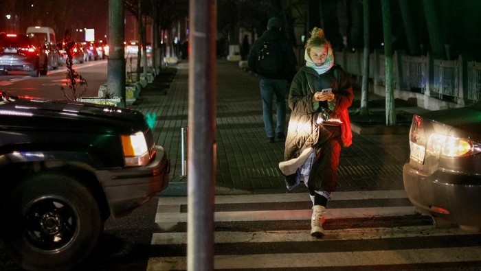 A woman crosses a street during a power blackout after critical civil infrastructure was hit by recent Russian missile and drone attacks, amid Russia's attack on Ukraine, in Kyiv, Ukraine December 9, 2025. REUTERS/Gleb Garanich