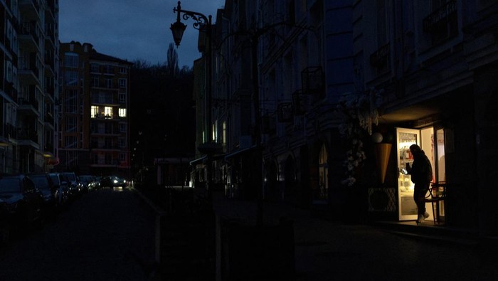 A man leaves a shop and steps into a dark street during a power blackout after critical civil infrastructure was hit by recent Russian missile and drone attacks, amid Russia's attack on Ukraine, in Kyiv, Ukraine December 10, 2025. REUTERS/Thomas Peter