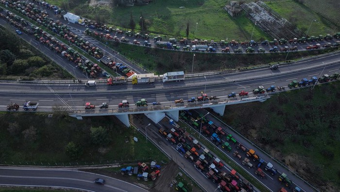 A drone view shows tractors of the Greek farmers, who are protesting over the delayed payment of European Union subsidies, blocking the national highway intersection near the city of Larissa, Greece, December 10, 2025. REUTERS/Louisa Gouliamaki     TPX IMAGES OF THE DAY