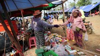 Warga jual beli kebutuhan pokok di kios darurat kamp, memanfaatkan pasokan terbatas yang tersedia. Banyak pengungsi di pagoda hanya membawa barang seperlunya dan kini sangat bergantung pada bantuan makanan serta air. REUTERS/Kim Hong-Ji