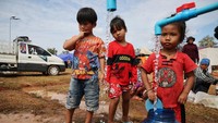 Anak-anak mengisi wadah air bersih yang didistribusikan ke area pengungsian sebagai bagian dari bantuan kemanusiaan. Di tempat perlindungan lain, anak-anak mencoba menjalani rutinitas meski harus berbagi ruang dengan ratusan pengungsi lainnya. REUTERS/Kim Hong-Ji