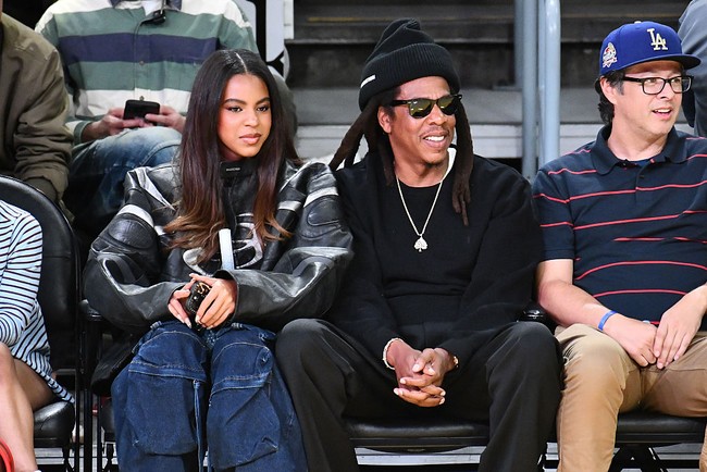 Ia melengkapi look-nya dengan wedge sneakers bertali, tas silver  dari Diesel, dan perhiasan berupa tumpukan kalung serta anting emas.  Foto: Getty Images/Allen Berezovsky