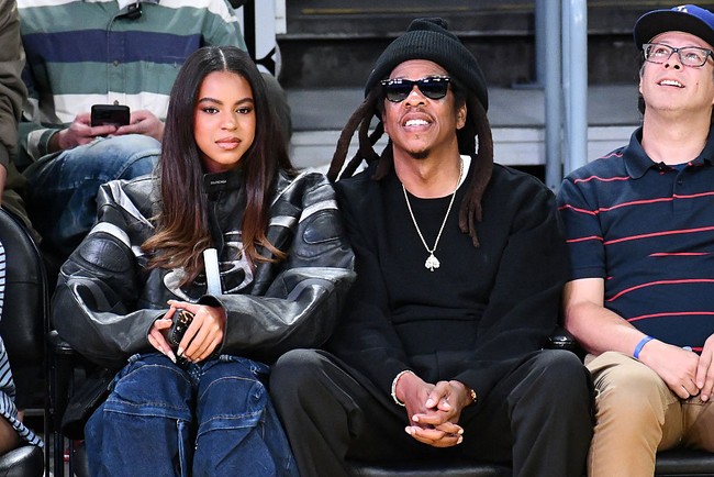 Sementara Jay-Z tampil lebih santai dengan busana serba hitam lengkap dengan sunglasses. Keduanya terlihat menikmati waktu bersama, tersenyum, dan berpose di kursi courtside. Foto: Getty Images/Allen Berezovsky