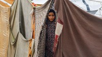 Seorang anak berdiri di ambang tenda yang basah. Laporan Reuters menyebut banyak tenda di Gaza tidak memiliki lantai atau isolasi, sehingga air hujan dengan mudah merembes ke dalam ruang tinggal pengungsi. REUTERS/Mahmoud Issa