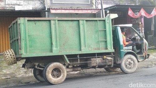 Kondisi truk sampah Dinas LH Tabanan tanpa pintu dengan tali darurat saat melintas di Jalan Pahlawan, Tabanan, Jumat (12/12/2025).
