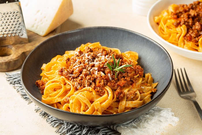 Close up of plates with Tagliatelle al ragu  - long, flat egg pasta with a meat sauce or Bolognese sauce and parmesan cheese, served with rosemary.