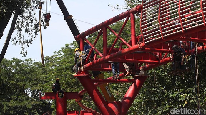 Para pekerja melakukan pembangunan jembatan penghubung (skybridge) pada proyek ruang terbuka hijau Taman Bendera Pusaka, Kramat Pela, Kebayoran Baru, Jakarta Selatan, Jumat (12/12/2025). Jembatan tersebut menghubungkan Taman Ayodya dan Taman Langsat. Bersama Taman Leuser, ketiganya akan disatukan menjadi Taman Bendera Pusaka.