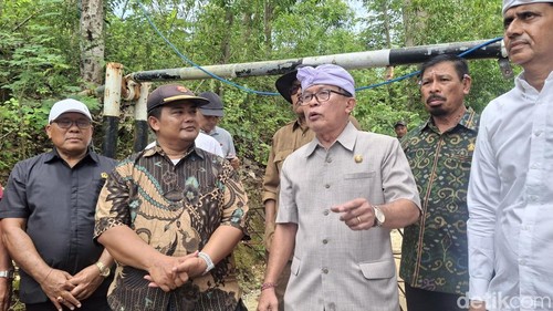 Satpol PP Bali membuka palang di Jalan Goa Petang Kacong II dan memasang garis polisi, Jumat (12/12/2025).