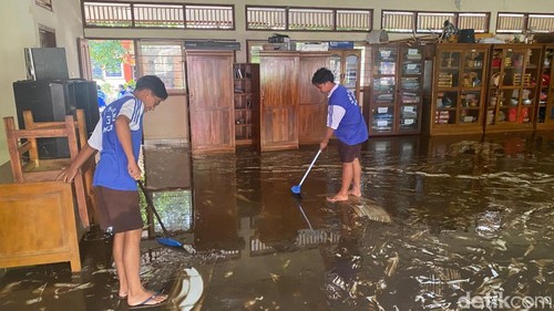 Sejumlah siswa SMPN 3 Manggis membersihkan sisa lumpur di ruang kelas mereka pada Jumat (12/12/2025). (Foto: I Wayan Selamat Juniasa/detikBali)