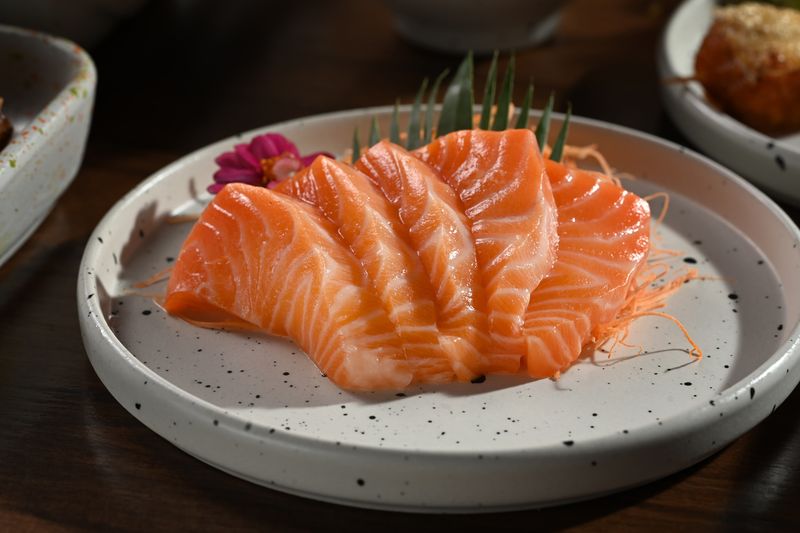 A plate of salmon sashimi on wooden table. Japanese food style concept.