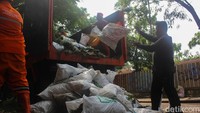 Petugas PPSU atau Pasukan Oranye mengumpulkan sampah dari waduk, sebagai upaya menjaga kebersihan lingkungan dan fungsi pengendali banjir.