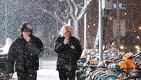 Masyarakat berjalan menyusuri jalanan bersalju saat salju perdana turun di Beijing, Jumat (12/12/2025). ANTARA FOTO/Desca Lidya Natalia