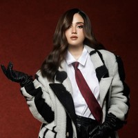 Syifa memadukan mantel tersebut dengan kemeja putih clean dan dasi merah burgundy bermotif garis, memberikan sentuhan maskulin. Untuk bawahannya ia tampak mengenakan celana kulit bertekstur warna hitam. Foto: Instagram/@syifahadju