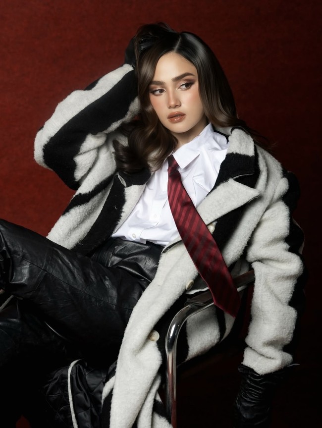 Ia mengenakan mantel berbahan tebal bernuansa hitam-putih. Mantel tersebut memiliki cutting oversized, memberi kesan bold, modern, sekaligus high fashion. Foto: Instagram/@syifahadju