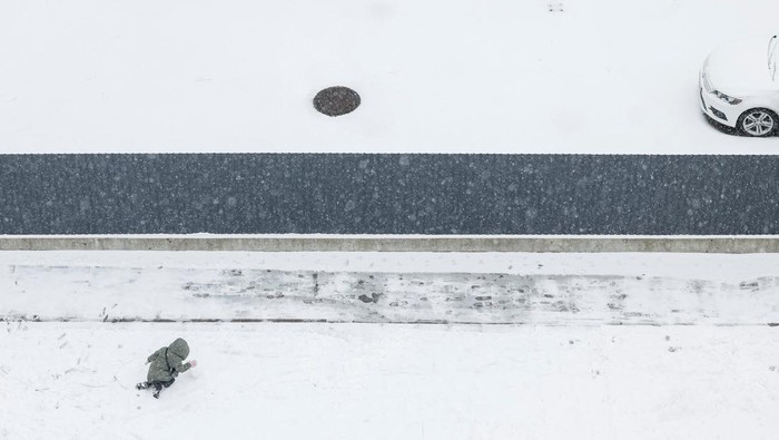 Salju pertama musim dingin turun di Kyiv, Ukraina, Minggu (14/12/2025), membawa momen langka kebahagiaan bagi anak-anak dan warga meski konflik dengan Rusia masih berlangsung. Di taman-taman bermain yang tertutup salju, anak-anak tampak riang membuat boneka salju dan bermain lempar salju, sementara orang tua mengawasi dengan senyum di wajah mereka. REUTERS/Gleb Garanich