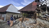 Penyintas bencana berjalan di samping rumah yang rusak akibat banjir bandang di Muaro Ambius, Nagari Guguak Malalo, Tanah Datar, Sumatera Barat, Sabtu (13/12/2025). Dengan peralatan seadanya, mereka menyusuri permukiman dan akses jalan yang terdampak, berusaha menyelamatkan barang-barang yang masih bisa digunakan. Upaya ini menjadi bagian dari proses pemulihan kehidupan sehari-hari setelah bencana melanda. ANTARA FOTO/Wahdi Septiawan