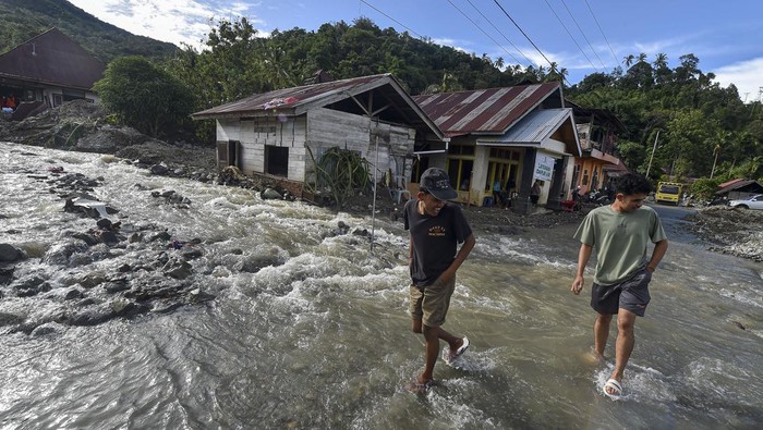 Warga melewati jalan yang terendam banjir di Muaro Ambius, Nagari Guguak Malalo, Tanah Datar, Sumatera Barat, Sabtu (13/12/2025). Hingga hari ke-17 pascabencana, sejumlah warga mulai beraktivitas di luar rumah untuk mengumpulkan barang-barang berharga miliknya yang rusak dan sempat hilang saat banjir bandang. ANTARA FOTO/Wahdi Septiawan/tom.