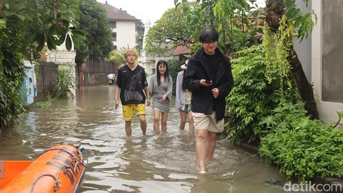 Sejumlah turis asing menerobos banjir di Jalan Gunung Athena, Denpasar, Bali, Minggu (14/12/2025). (Foto: Aryo Mahendro/detikBali)