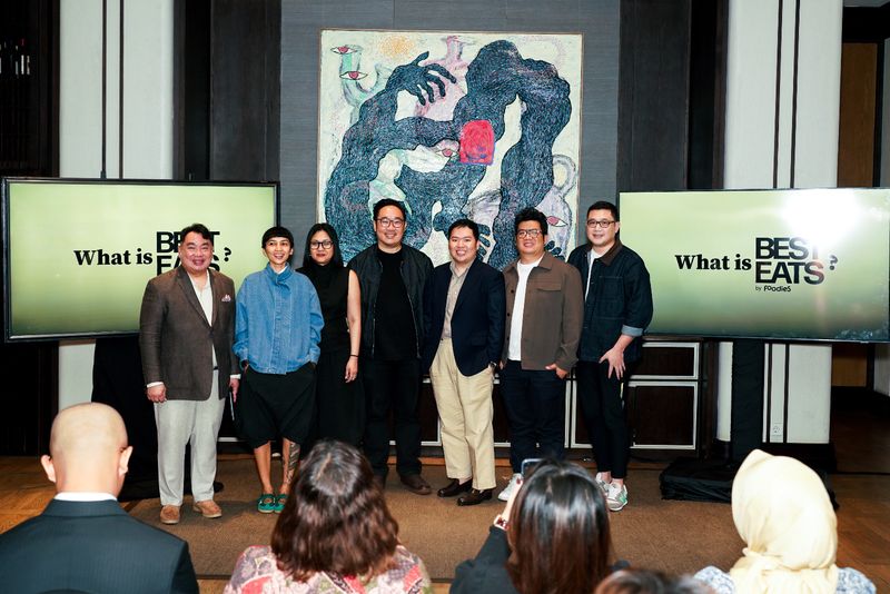 1428412216 A male chef pouring sauce from the spoon on meal on a black background.