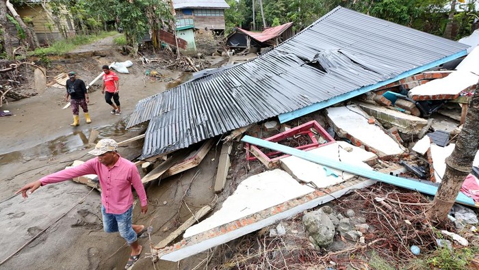 Warga melintas di dekat rumah yang hancur akibat bencana banjir bandang di Desa Alue Kuta, Kecamatan Jangka, Bireuen, Aceh, Minggu (14/12/2025). Data sementara posko tanggap darurat bencana hidrometeorologi Aceh menyebutkan sebanyak 1.232 unit rumah warga di 609 desa yang tersebar di 17 kecamatan tertimbun lumpur serta rusak berat akibat bencana banjir bandang. ANTARA FOTO/Irwansyah Putra/agr