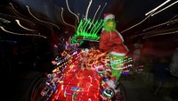 Peserta berkostum Grinch bergaya di atas mobil yang dipenuhi lampu Natal saat mengikuti Christmas Light Car Convoy di Cape Town. Konvoi ini digagas komunitas warga dan rutin digelar setiap Desember menjelang Natal. REUTERS/Esa Alexander