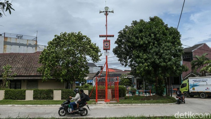 Pengendara melintas di depan mesin Early Warning System (EWS) banjir di Bekasi, Senin (15/12/2025). Dipasangnya early warning system (EWS) banjir di sejumlah titik rawan ini untuk memperkuat mitigasi bencana saat musim hujan. Perangkat peringatan dini ini tersebar di wilayah yang berada di sepanjang aliran sungai dan kawasan permukiman yang kerap terdampak luapan air, khususnya di Daerah Aliran Sungai (DAS) Kali Bekasi dan sekitarnya.