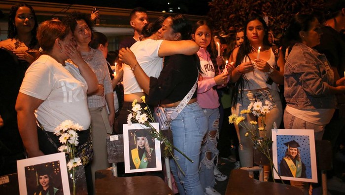 A woman arranges school desks displaying photographs of students during a vigil for victims of a bus accident, outside the Liceo Antioqueno in Bello, Colombia, December 14, 2025. REUTERS/Juan David Duque