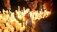 Seorang peserta vigili berdiri sambil menyalakan lilin, menatap ke arah sekolah, mengenang para siswa yang tak lagi kembali. REUTERS/Juan David Duque