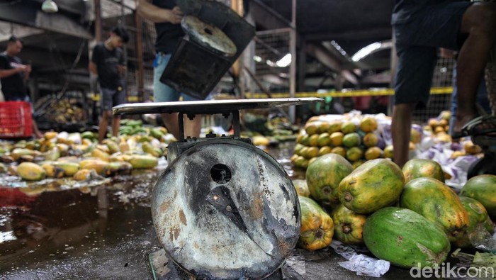 Los Pepaya Kramat Jati Terbakar, Pedagang Pilah Buah Tersisa Para pedagang menyortir pepaya yang masih bisa diselamatkan usai kebakaran melanda los buah di Pasar Induk Kramat Jati, Jakarta Timur, Senin (15/12/2025).