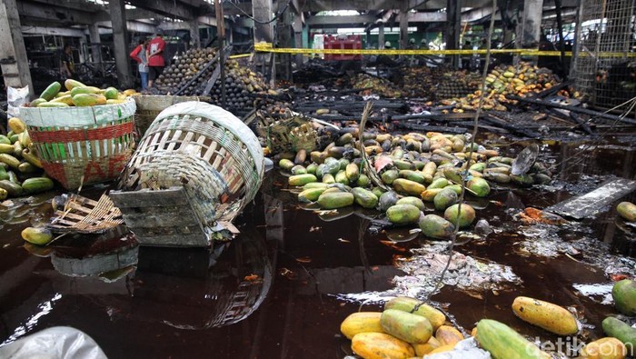 Para pedagang menyortir pepaya yang masih bisa diselamatkan usai kebakaran melanda los buah di Pasar Induk Kramat Jati, Jakarta Timur, Senin (15/12/2025).