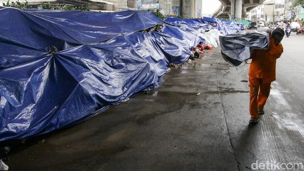 Sampah di Ciputat Menggunung, Ditutup Terpal Sementara Sejumlah warga merapikan tumpukan sampah di kawasan Ciputat, Tangerang Selatan, Banten, Senin (15/12/2025).