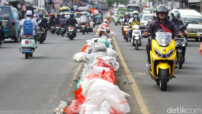 Sejumlah warga merapikan tumpukan sampah di kawasan Ciputat, Tangerang Selatan, Banten, Senin (15/12/2025).
