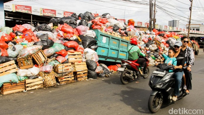 Sejumlah warga saat melintas di Jalan Jombang Raya, Ciputat, Tangerang Selatan, Senin (15/12/2025). Tumpukan sampah setinggi sekitar dua meter ini telah mengendap lebih dari sepekan akibat penutupan Tempat Pembuangan Akhir (TPA) Cipeucang.