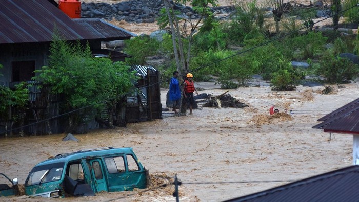 Tim SAR memandu warga menyeberangi air menggunakan tali di kawasan Batu Busuk, Pauh, Padang, Sumatera Barat, Minggu (14/12/2025). Air sungai di permukiman terdampak banjir bandang tersebut kembali meluap dan membuat sejumlah warga dievakuasi ke tempat yang lebih aman. ANTARA FOTO/Iggoy el Fitra/agr