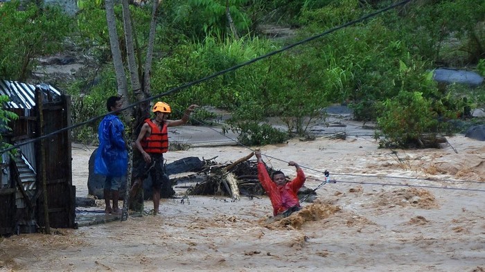 Tim SAR memandu warga menyeberangi air menggunakan tali di kawasan Batu Busuk, Pauh, Padang, Sumatera Barat, Minggu (14/12/2025). Air sungai di permukiman terdampak banjir bandang tersebut kembali meluap dan membuat sejumlah warga dievakuasi ke tempat yang lebih aman. ANTARA FOTO/Iggoy el Fitra/agr