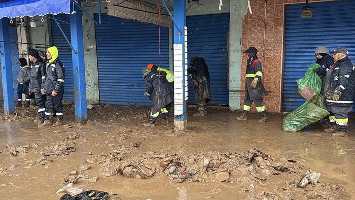 SAFI, MOROCCO - DECEMBER 15: People are trying to walk down the mud covered street as teams continue their work across the city to repair and clean up the damage caused by the flood in the mud covered streets of the Safi, Morocco on December 15, 2025. The death toll from flash floods in the western city of Safi rose to 21, Moroccan authorities announced. Search and rescue operations are ongoing, and necessary measures have been taken to secure the affected areas and provide support to residents, it added. (Photo by Stringer/Anadolu via Getty Images)