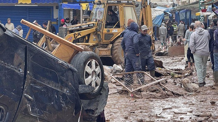SAFI, MOROCCO - DECEMBER 15: People are trying to walk down the mud covered street as teams continue their work across the city to repair and clean up the damage caused by the flood in the mud covered streets of the Safi, Morocco on December 15, 2025. The death toll from flash floods in the western city of Safi rose to 21, Moroccan authorities announced. Search and rescue operations are ongoing, and necessary measures have been taken to secure the affected areas and provide support to residents, it added. (Photo by Stringer/Anadolu via Getty Images)
