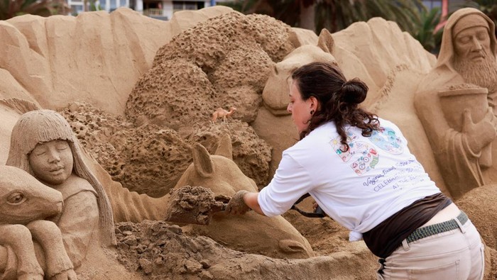 Two tourists take a photo next to a sand sculpture representing a Christian nativity scene on Las Canteras beach in Las Palmas de Gran Canaria, Spain, December 15, 2025. REUTERS/Borja Suarez